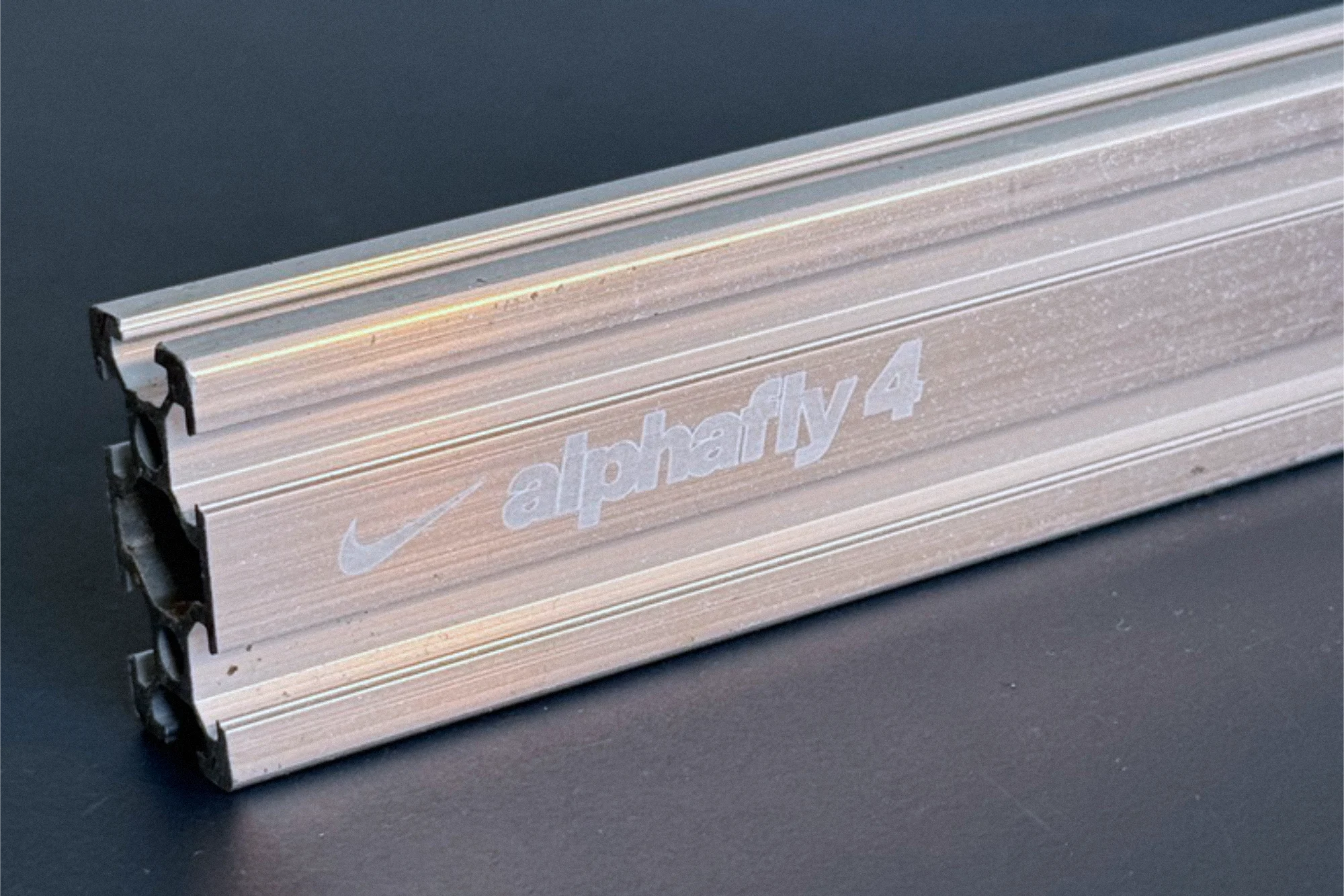 Close-up of an aluminium extrusion profile with the Nike swoosh and alphafly 4 engraved into the flat face